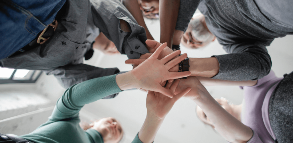 A group of people putting their hands together in a circle