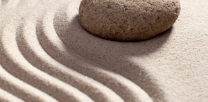 Building a Culture of Hard Work - closeup of a rock on sand with wavy lines