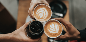 Self care - people tapping 2 cups of coffee against another glass drink