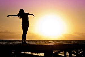 Person in the sunset, lifting arms and raising face to the sky