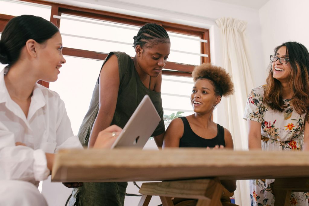 A group of women talking and laughing in the workplace, presenting a positive company culture